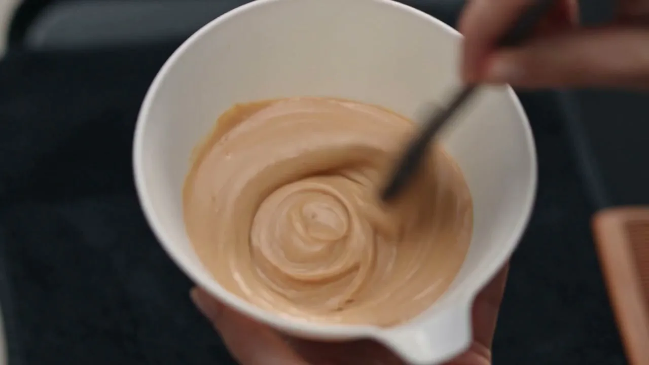 Gloss swirled in a plain white bowl, mixed at the chair